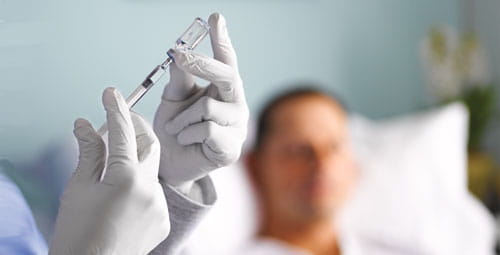 A nurse extracting medication from a vial into a syringe