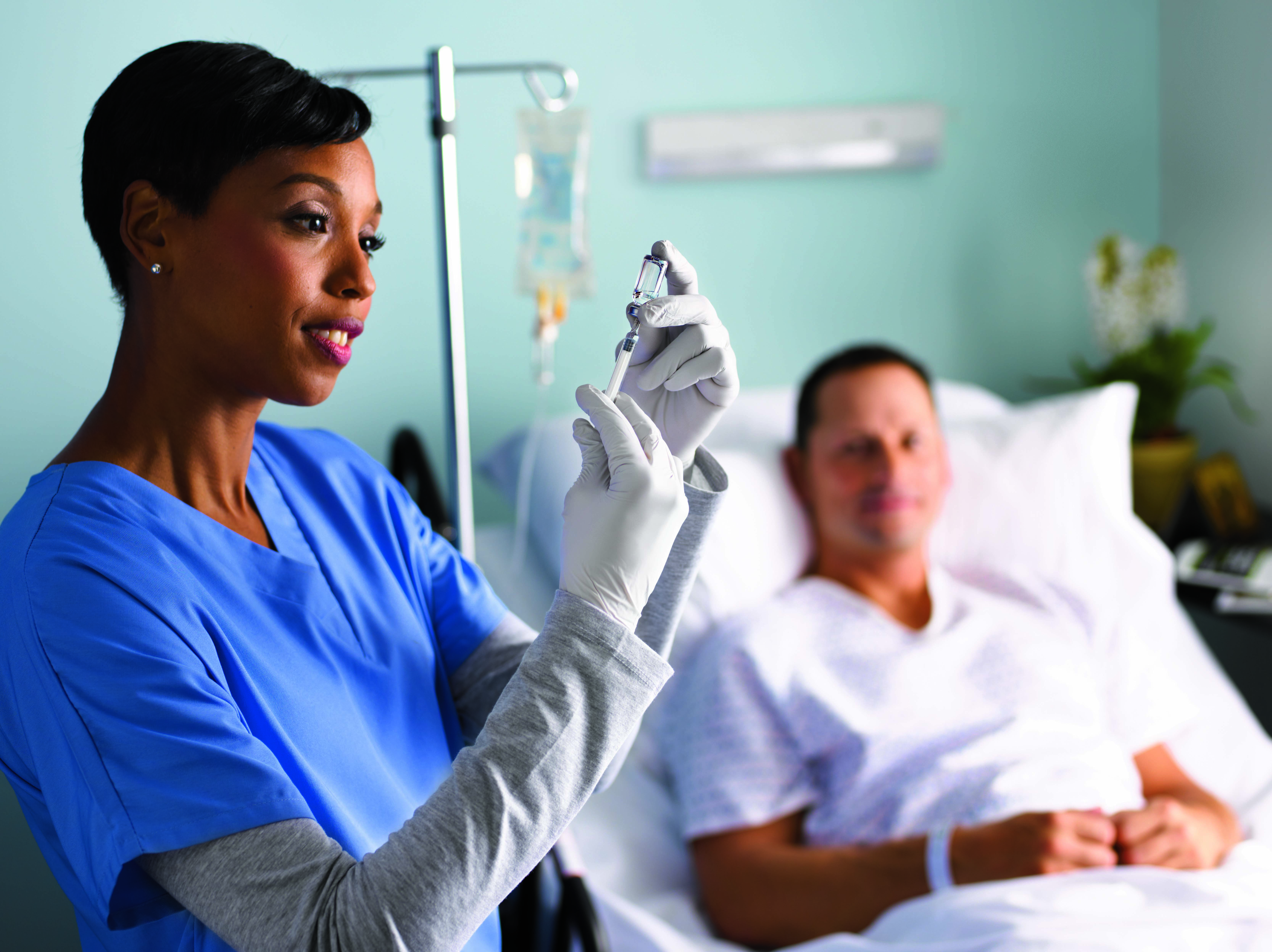 Gloved hand drawing medication from a vial with a syringe, highlighting injection safety.
