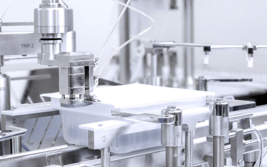 Automated pharmaceutical filling equipment handling nested containers in a sterile manufacturing environment.