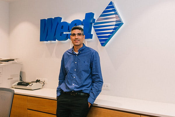 West Employee in front of the West Logo Sign