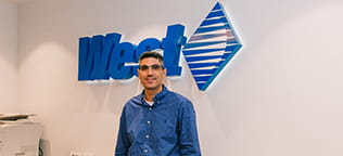 West Employee standing in front of the West logo sign