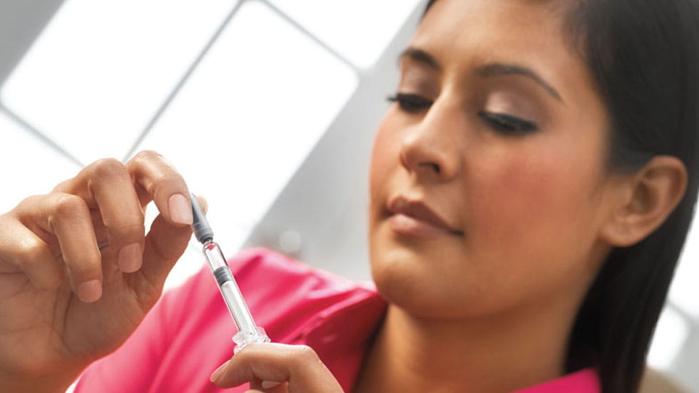Patient taking a rigid needle shield off of West Insert Needle Syringe Delivery System for use